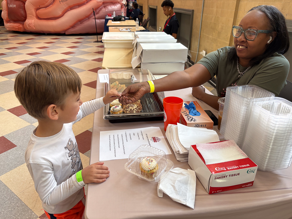 IMG_0347 At a birthday table, a woman gives a cupcake to a child while they exchange a Breadcoin.