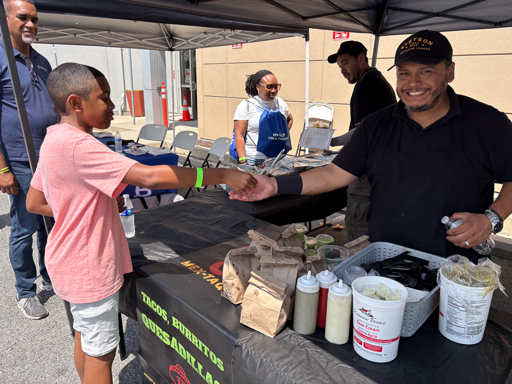 IMG_0352 A man and boy at a food stand, exchanging Bredcoin for a birthday meal.
